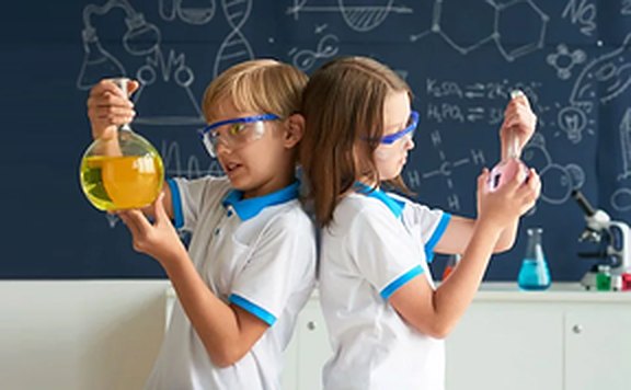 Two students in safety goggles holding flasks during a hands-on science lesson